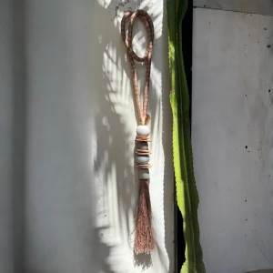 Detalle de un collar decorativo rústico para mesa, hecho con materiales naturales y cuero