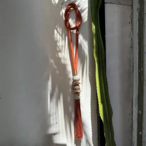 Colgante decorativo alargado hecho con cuentas artesanales y una tira de cuero para colgar