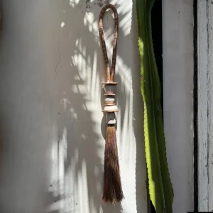 Colgante ornamental rústico de cuentas artesanales y cuero puesto contra un fondo claro