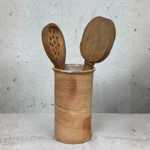 Portacucharas de cerámica que contiene dos cucharas de madera de cocina.