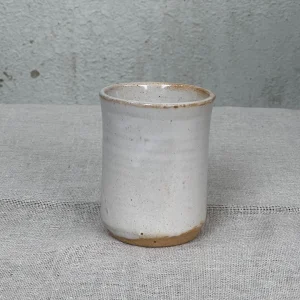 Vaso de cerámica artesanal blanca con borde rústico, ideal para café espresso.
